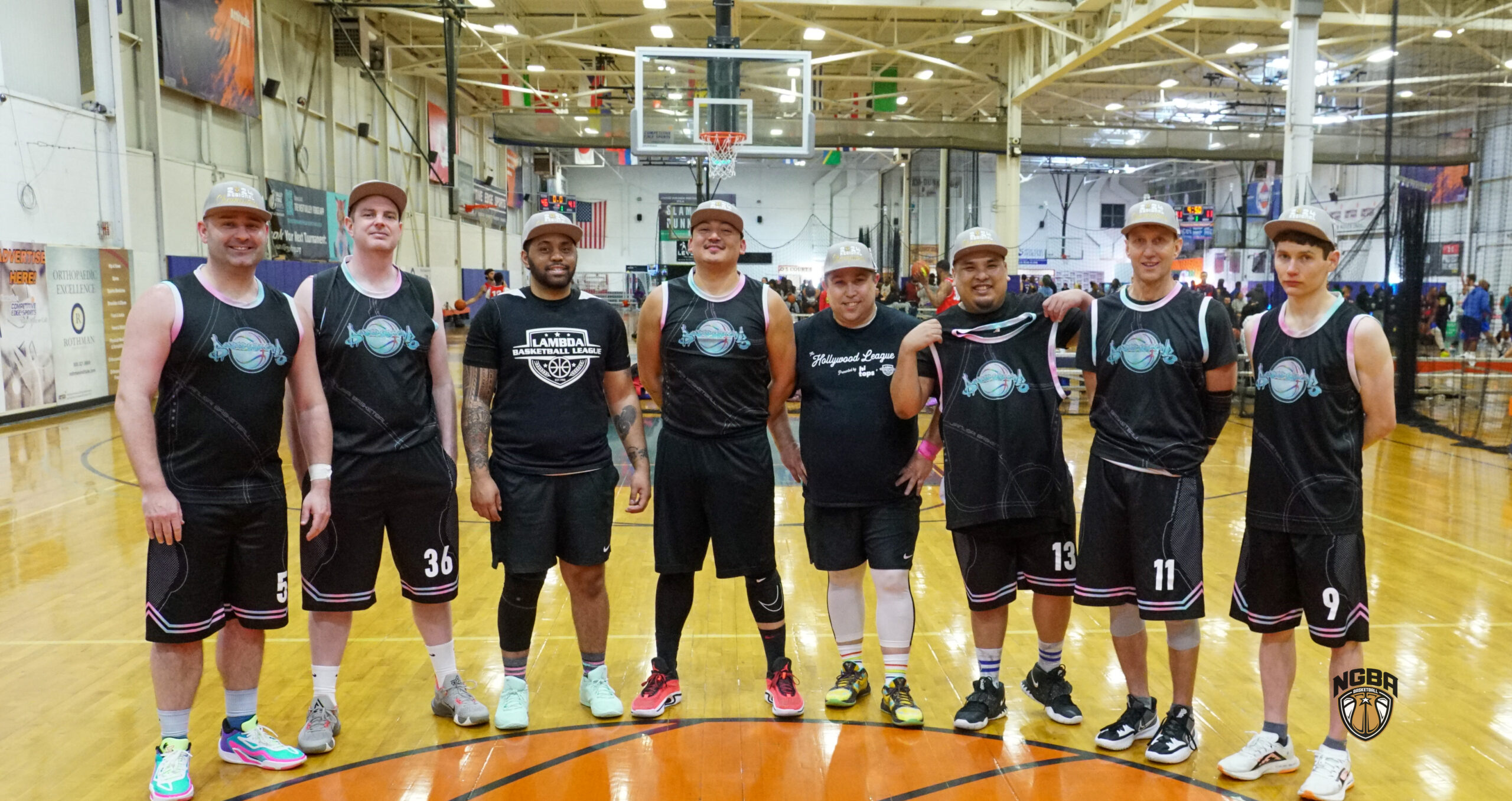 8 Men wearing basketball jerseys and championship hats pose for picture