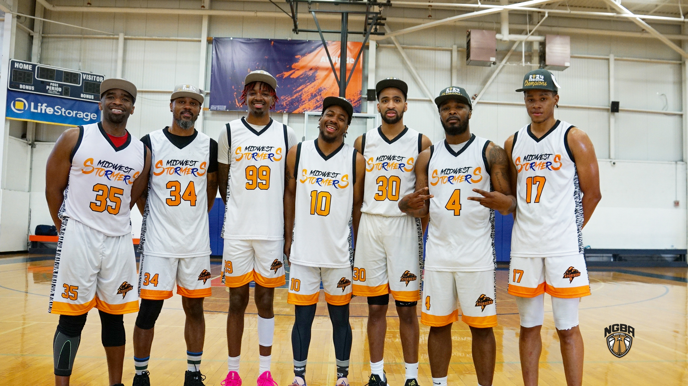 8 Men wearing basketball jerseys and championship hats pose in for picture