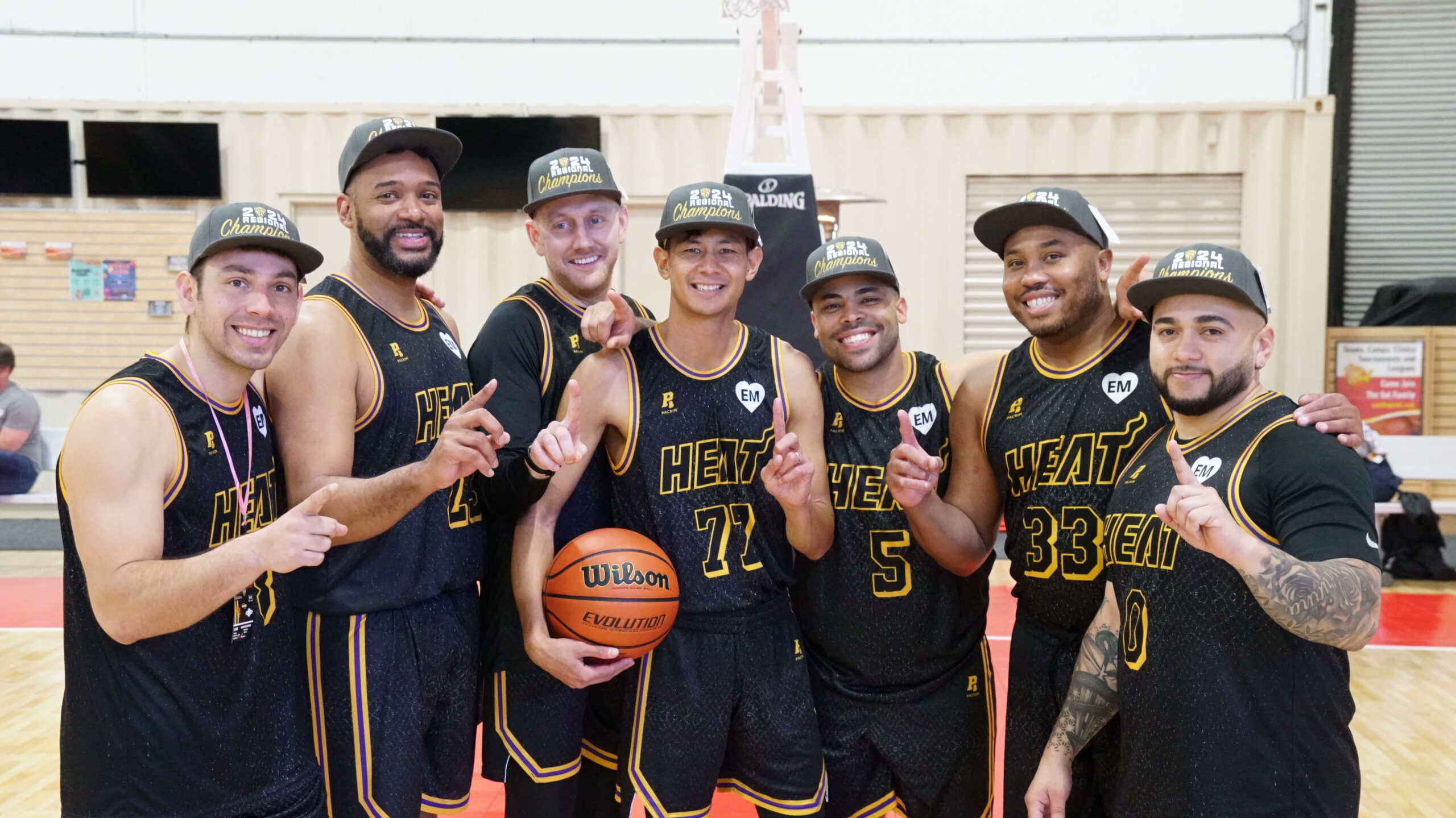 7 Men wearing basketball jerseys and championship hats pose for picture