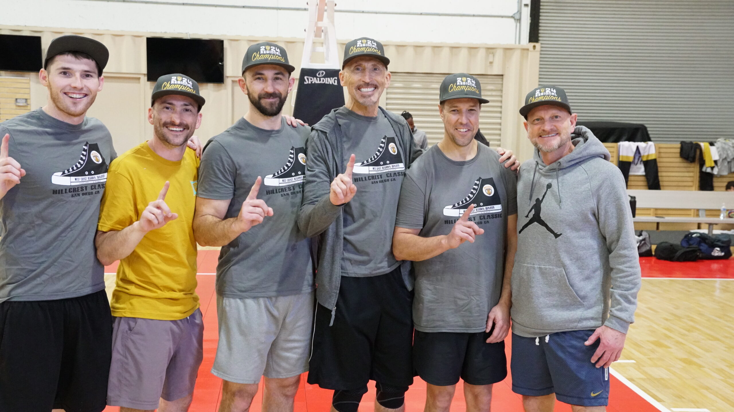 6 Men wearing basketball jerseys and championship hats pose for picture